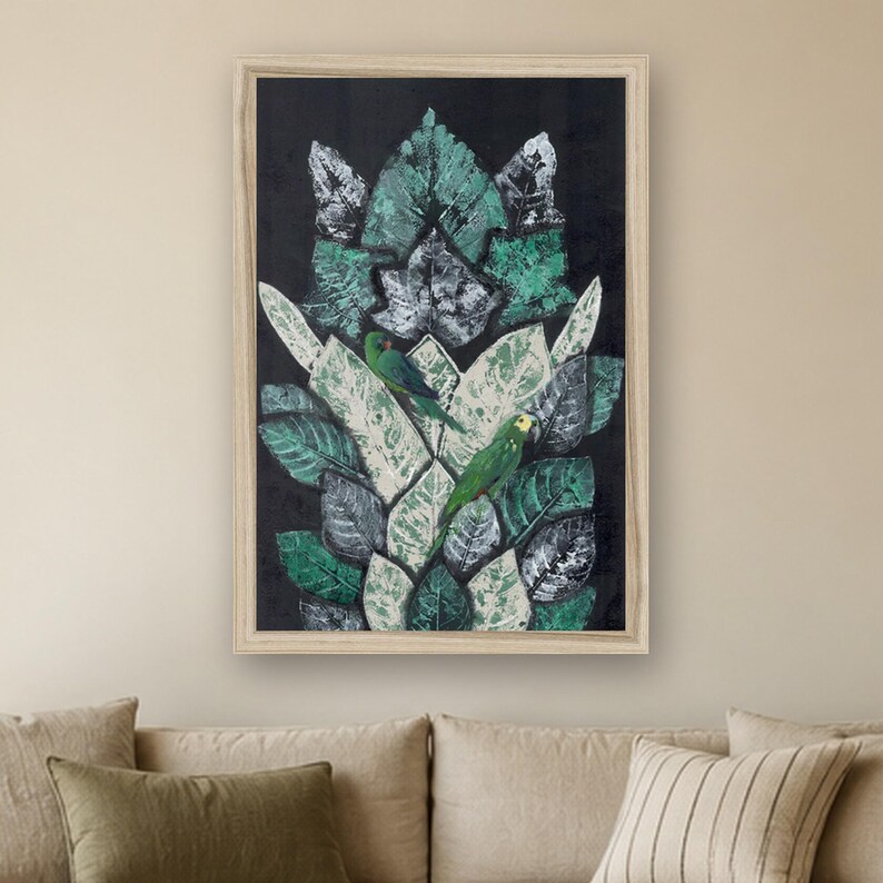May include: A framed rectangular wall art piece featuring a dark black background with a central vertical arrangement of layered green and white leaves. Two small green parrots with yellow accents are perched among the foliage.