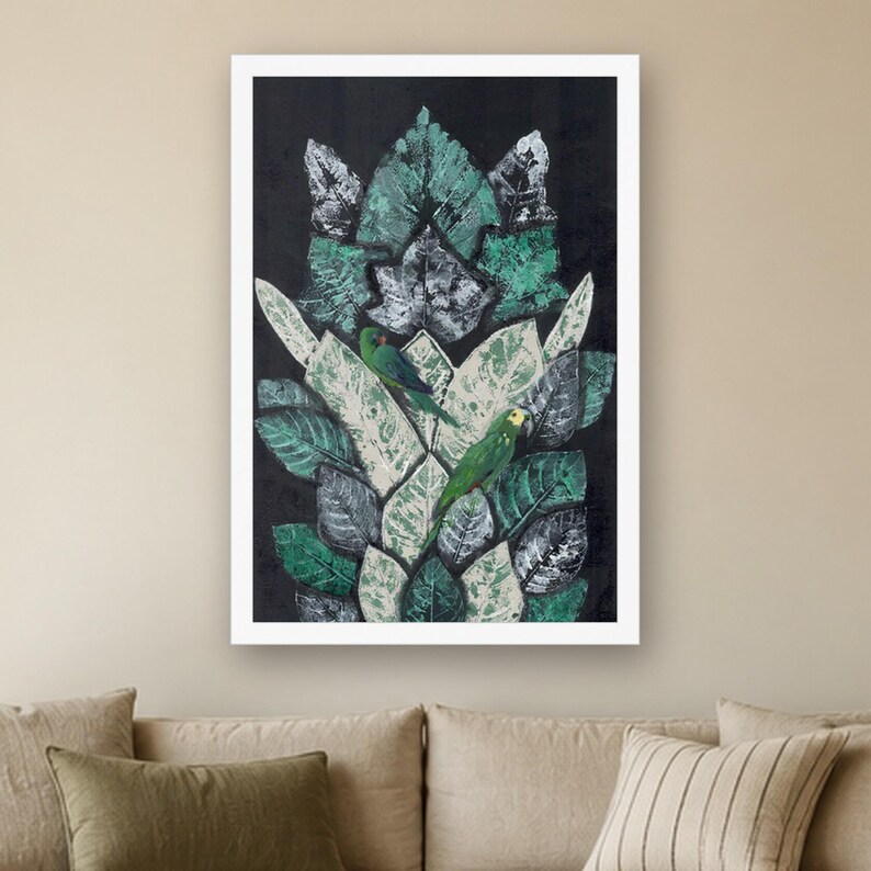 May include: A framed rectangular wall art print featuring a vertical arrangement of layered, textured leaves in shades of dark green, light green, and white against a solid black background, with two small green parrots perched among them.