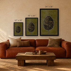 May include: Three framed wall art prints featuring a dark leaf illustration on a muted olive green background. The prints are labeled with dimensions of 12" x 18", 16" x 24", and 24" x 36" respectively, displayed in black frames.