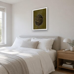 May include: A rectangular wall art print featuring a dark olive green background with a central black and gold leaf illustration. The leaf has detailed veins and is topped with a small cluster of black dots, all encased in a white frame.