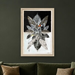 May include: A framed wall art print featuring a symmetrical arrangement of gray and black leaves. A toucan with an orange beak and a white cockatoo with a yellow crest are perched among the foliage. The background is split between black and white.