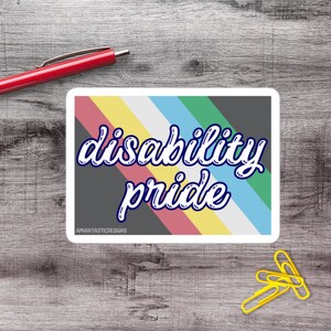 Puede incluir: Una pegatina rectangular con las palabras "disability pride" en escritura blanca sobre un fondo gris con rayas diagonales en colores arcoíris. La pegatina tiene un borde blanco y el texto "APHANTASTICDESIGNS" en la parte inferior.