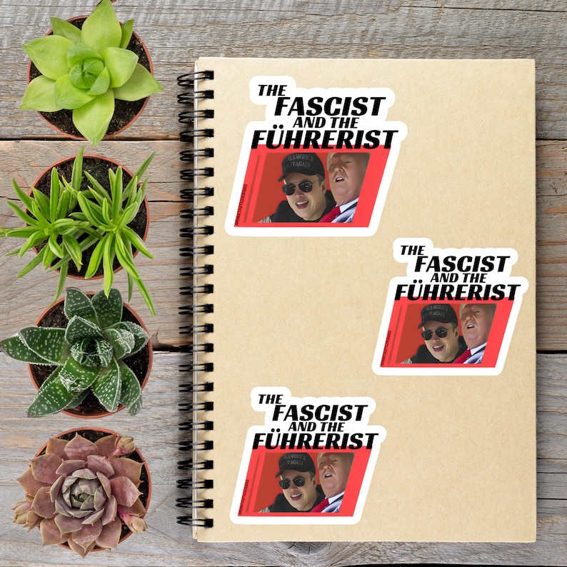 a spiral notebook with stickers on it, along with several potted plants arranged on a wooden surface.