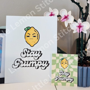 May include: Two prints with a yellow lemon cartoon with a grumpy expression and the text "Stay Grumpy". The larger print has a white background and the smaller print has a green and white checkered background.