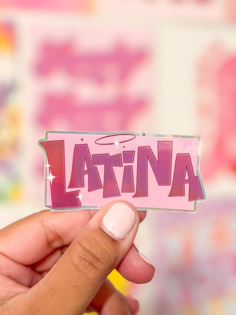 Puede incluir: Una pegatina hologr&aacute;fica rosa y morada con la palabra "LATINA" en letras blancas en negrita con un halo sobre la palabra.