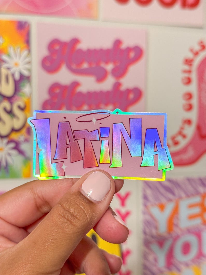 Puede incluir: Una pegatina hologr&aacute;fica con la palabra "LATINA" en letras rosas, azules y verdes sobre un fondo arco&iacute;ris iridiscente.