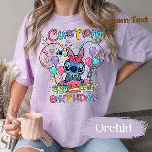 May include: Orchid-colored t-shirt featuring a cartoon character with a birthday cake, balloons, and the words "Custom Birthday." The design includes colorful accents and gift boxes, creating a festive look.