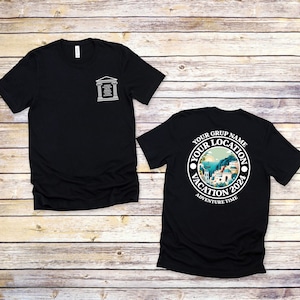 May include: Two black t-shirts with a white graphic design. The front shirt has a white graphic of a building with text. The back shirt has a white graphic of a circle with text that says "Your Grup Name Your Location Vacation 2024 Adventure Time".