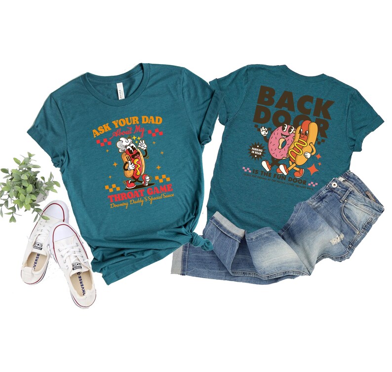 Puede incluir: Camisetas de color turquesa con gr&aacute;ficos de dibujos animados de perritos calientes y donuts. Una camiseta dice "Ask Your Dad About My Throat Game" y la otra "Back Door". Las camisetas se combinan con vaqueros azules y zapatillas blancas.