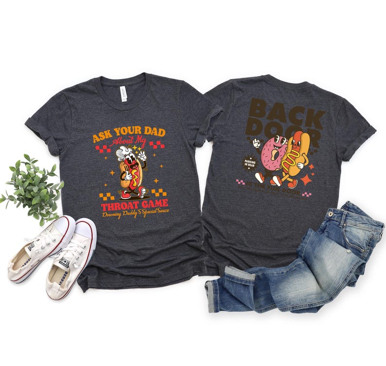 Puede incluir: Camisetas de color gris oscuro con gr&aacute;ficos delanteros y traseros. La parte delantera presenta un perrito caliente de dibujos animados con el texto "Ask Your Dad About My Throat Game". La parte trasera muestra un donut y un perrito caliente con el texto "Back Door."
