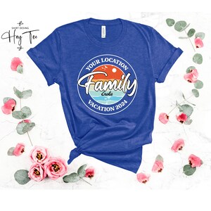 K&ouml;nnte beinhalten: Ein k&ouml;nigsblaues T-Shirt mit einem wei&szlig;en Kreis-Motiv, auf dem "Your Location Family Vacation 2024" steht, mit einem Sonnenuntergang und Palmen im Kreis. Der Text "Enola" befindet sich im Kreis.