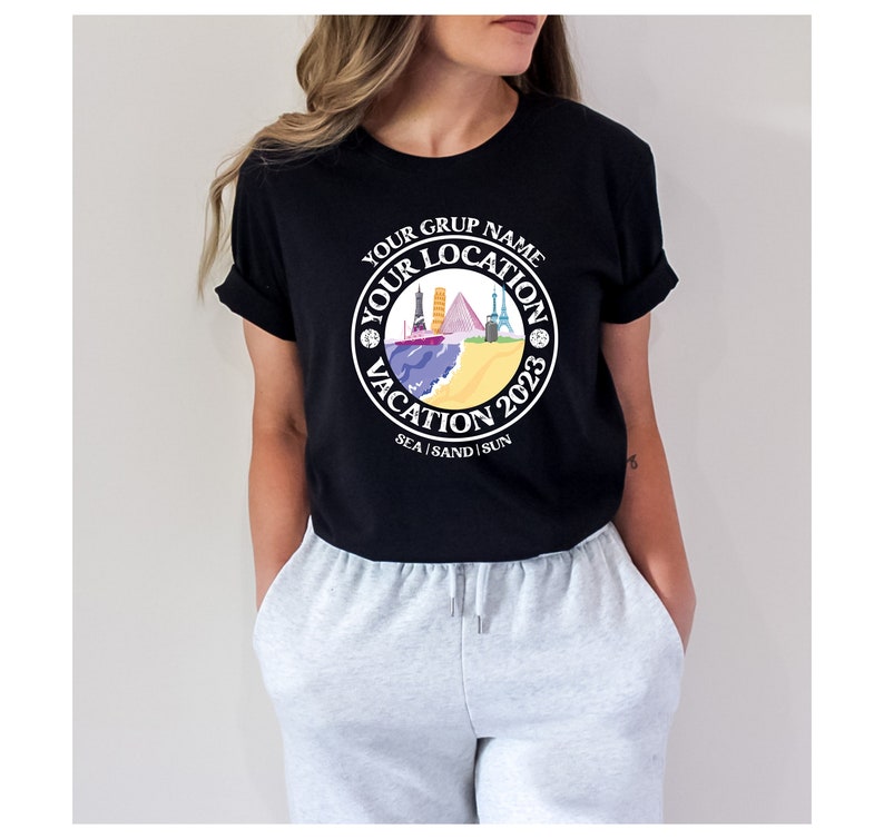May include: Black t-shirt with a white circle graphic featuring the text "Your Grup Name Your Location Vacation 2023 Sea | Sand | Sun" and a colorful illustration of various landmarks.
