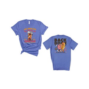 Puede incluir: Dos camisetas azules con dise&ntilde;os gr&aacute;ficos. Una camiseta presenta un perrito caliente de dibujos animados con el texto "Ask Your Dad About Funny Game". La otra camiseta tiene un perrito caliente y una rosquilla de dibujos animados con el texto "Back Door Is The Fun Door".