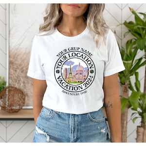 K&ouml;nnte beinhalten: Wei&szlig;es T-Shirt mit einem schwarzen Kreis-Motiv, das eine Stadtlandschaft mit dem Text "Your Grup Name Your Location Vacation 2024 Adventure Time" zeigt.