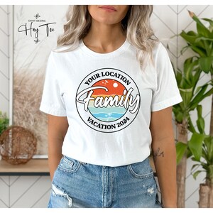 K&ouml;nnte beinhalten: Wei&szlig;es T-Shirt mit einem Retro-Kreis-Motiv, auf dem "Your Location Family Vacation 2024" steht.