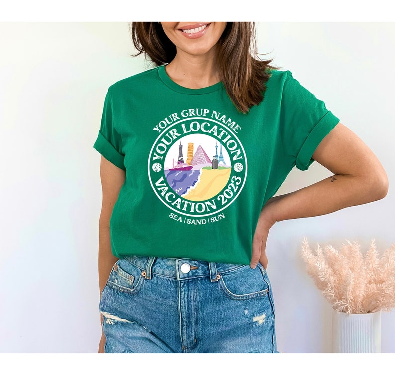 May include: Green t-shirt with a white circle graphic that says "Your Grup Name Your Location Vacation 2023 Sea Sand Sun". The graphic features a beach scene with colorful buildings and a boat.