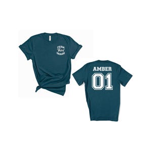 May include: Two teal t-shirts. One has "Team Third Grade" printed on the front. The other has "Amber 01" printed on the back. The shirts are short-sleeved and made of a soft material.
