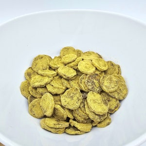 May include: A white bowl filled with a large amount of dried banana chips. The chips are a light yellow color and have a slightly brown hue.