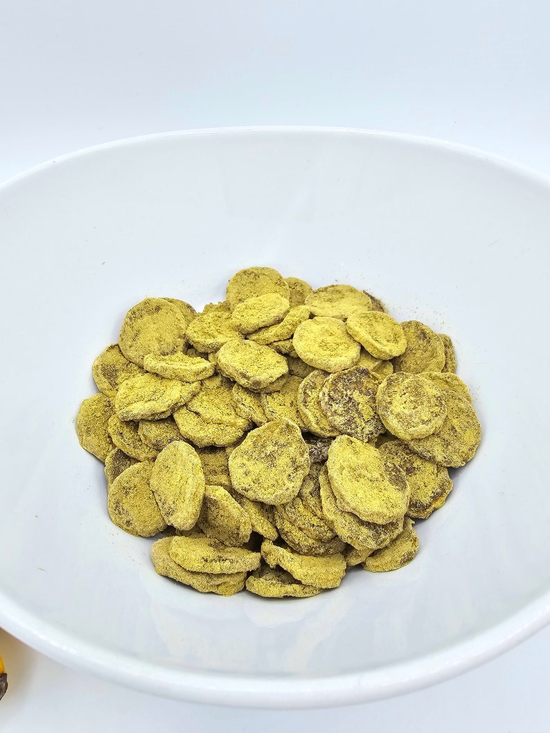 May include: A white bowl filled with a large amount of dried banana chips. The chips are a light yellow color and have a slightly brown hue.