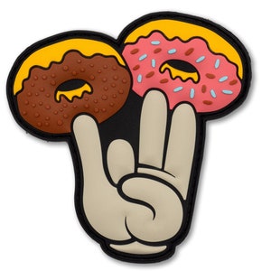 May include: A patch featuring a cartoon hand holding two donuts. One donut is brown with yellow icing, the other is pink with blue sprinkles and yellow icing. The hand is beige with a black outline.