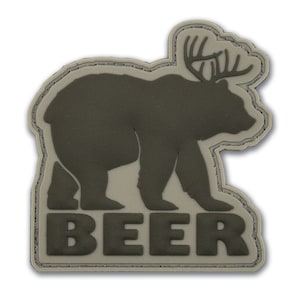 May include: A patch featuring a bear with antlers, in a dark green color. The word "BEER" is displayed in bold letters at the bottom. The patch has a light tan border and a stitched edge.