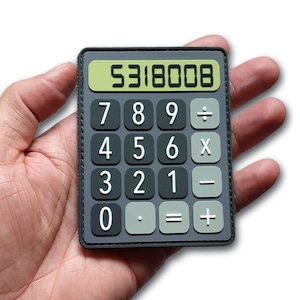 May include: A gray calculator patch with white numbers and a green display showing "5318008." The calculator has a black border and is held in a hand. The calculator buttons include numbers, and mathematical symbols.
