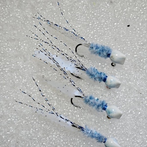 May include: Four white and blue fly fishing lures with white and blue feathers and a white bead head.