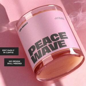 May include: A pink glass candle jar with a white label that says "Peace Wave" and "5.8 oz Soy Wax Candle". The candle is on a pink surface.