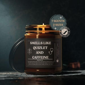 Puede incluir: Una vela de vidrio marrón con una etiqueta negra que dice "Smells Like Quizlet and Caffeine". La vela está sobre una superficie oscura. La etiqueta también incluye un símbolo médico, un estetoscopio y el texto "Scent No. 23".