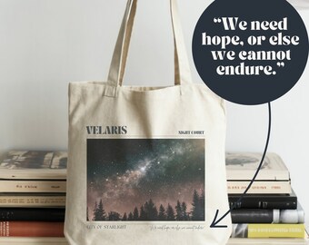 May include: A beige tote bag featuring a starry night design with the words "VELARIS" and "NIGHT COURT." The bag also includes the quote, "We need hope, or else we cannot endure." The image shows a forest silhouette under a vibrant galaxy.