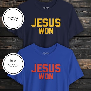 May include: Two short-sleeve crew neck t-shirts. The top shirt is navy blue with yellow text that reads JESUS WON. The bottom shirt is true royal blue with orange text that reads JESUS WON. Both shirts feature the brand name GENESIS at the neckline.