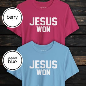 May include: Two short-sleeve crew neck t-shirts, one in berry and one in ocean blue. Both shirts feature the text "JESUS WON" in bold white block lettering on the chest and the brand name "GENESIS" printed in small white letters near the neckline.