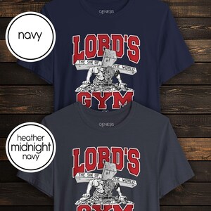 Puede incluir: Dos camisetas de manga corta en azul marino y azul marino medianoche jaspeado. El gr&aacute;fico muestra una figura empujando una cruz de madera con el texto "LORD'S GYM" en rojo y "THE SIN OF THE WORLD" en la cruz. La marca "GENESIS" aparece en el cuello.