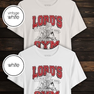 Puede incluir: Dos camisetas de manga corta y cuello redondo en blanco vintage y blanco. El gr&aacute;fico presenta el texto rojo LORD'S GYM con una ilustraci&oacute;n en blanco y negro de una figura cargando una cruz de madera, con el texto THE SIN OF THE WORLD.