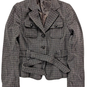 Peut inclure: Veste à motif pied-de-poule gris et noir. La veste a un col cranté, deux poches avant et une ceinture assortie qui se noue à la taille. Elle possède une fermeture à boutons et une doublure foncée.