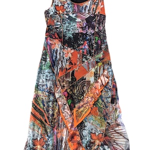 May include: Sleeveless dress with a vibrant, abstract print. The dress features a patchwork design with orange, black, and blue accents. The fabric has a flowing, asymmetrical hemline. The dress has a scoop neckline and a dark lining.