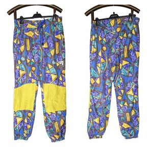 May include: A pair of blue, yellow, purple, and brown patterned pants with a drawstring waist. The pants have yellow panels on the knees.