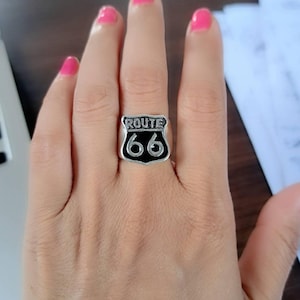 May include: A silver ring with a black enamel Route 66 sign.
