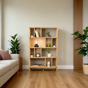 K&ouml;nnte beinhalten: Ein B&uuml;cherregal aus Holz mit mehreren Regalbrettern und F&auml;chern. Die Regalbretter sind mit B&uuml;chern, einer Lampe, einer Uhr und Dekoartikeln gef&uuml;llt. Das B&uuml;cherregal steht auf einem Holzboden.