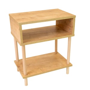 May include: A light wood end table with two shelves and four turned legs. The table is made of a light wood with a natural finish.