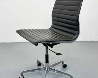 Peut inclure: Chaise de bureau noire avec dossier et assise côtelés, montée sur un piètement chromé à cinq roulettes. La chaise dispose d'un levier de réglage en hauteur et d'un design élégant et moderne.