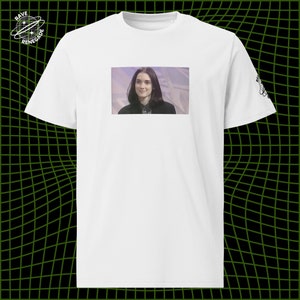 May include: White t-shirt with a printed image of a woman with dark hair looking at the camera.