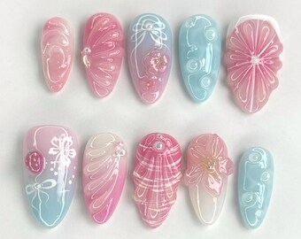 Può includere: Dieci unghie finte ovali con un design sfumato bianco e rosa. Ogni unghia presenta un diverso design floreale bianco.
