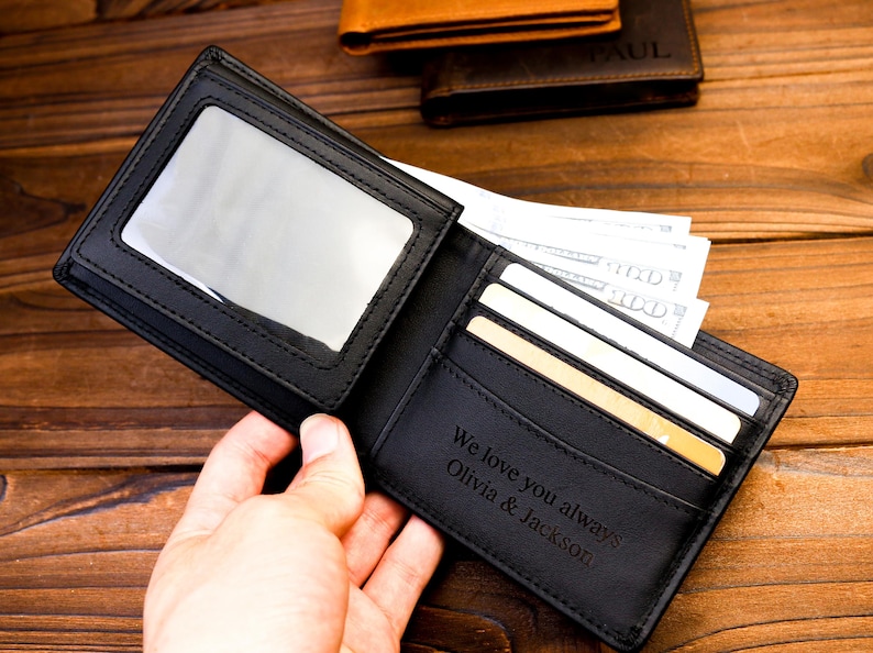 Puede incluir: Cartera de cuero negro con una ventana de pl&aacute;stico transparente para una identificaci&oacute;n con foto. La cartera tiene m&uacute;ltiples ranuras para tarjetas y un bolsillo para efectivo. La cartera est&aacute; personalizada con el texto "We love you always Olivia & Jackson".
