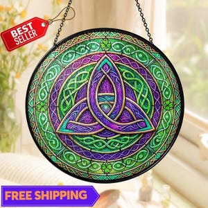 May include: Round stained glass window with a Celtic knot design in shades of green, purple, and gold. The window is hanging from a chain and has a black border. A red tag that says "BEST SELLER" is attached.