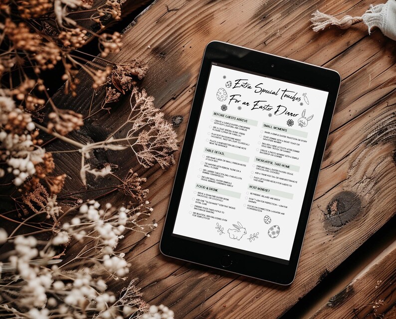 Op de afbeelding: Een zwarte tablet met een menu getiteld "Extra Special Touches For an Easter Dinner" met paasillustraties. De tablet ligt op een rustiek houten oppervlak, met gedroogde bloemstukken op de achtergrond.