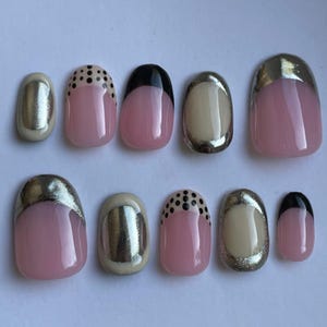 May include: Set of ten false nails with different designs. Some nails have a silver accent, some have black polka dots, and some have a black tip.