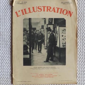 Puede incluir: Portada de revista vintage "L'Illustration" con texto rojo. La portada presenta una fotografía en blanco y negro de hombres con trajes y sombreros de copa en un museo. La fecha es el 12 de diciembre de 1931.