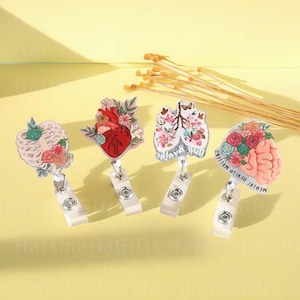 May include: Four medical-themed badge reels featuring anatomical designs: a rib cage, a heart, lungs, and a brain. Each reel is decorated with floral accents and glitter. The brain reel has the text "MENTAL HEALTH MATTERS".