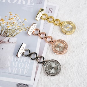 Könnte beinhalten: Drei Taschenuhren in Gold, Roségold und Silber mit Kette und personalisiertem Namensschild. Die Namensschilder tragen die Aufschrift "Linda", "Anna" und "Lisa".
